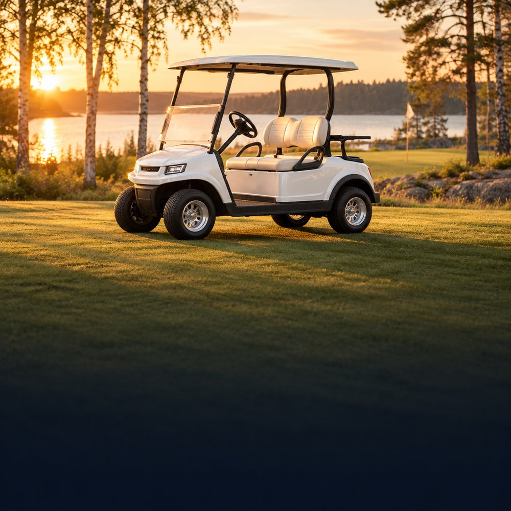 Vit golfbil på en golfbana vid en sjö i kvällssol